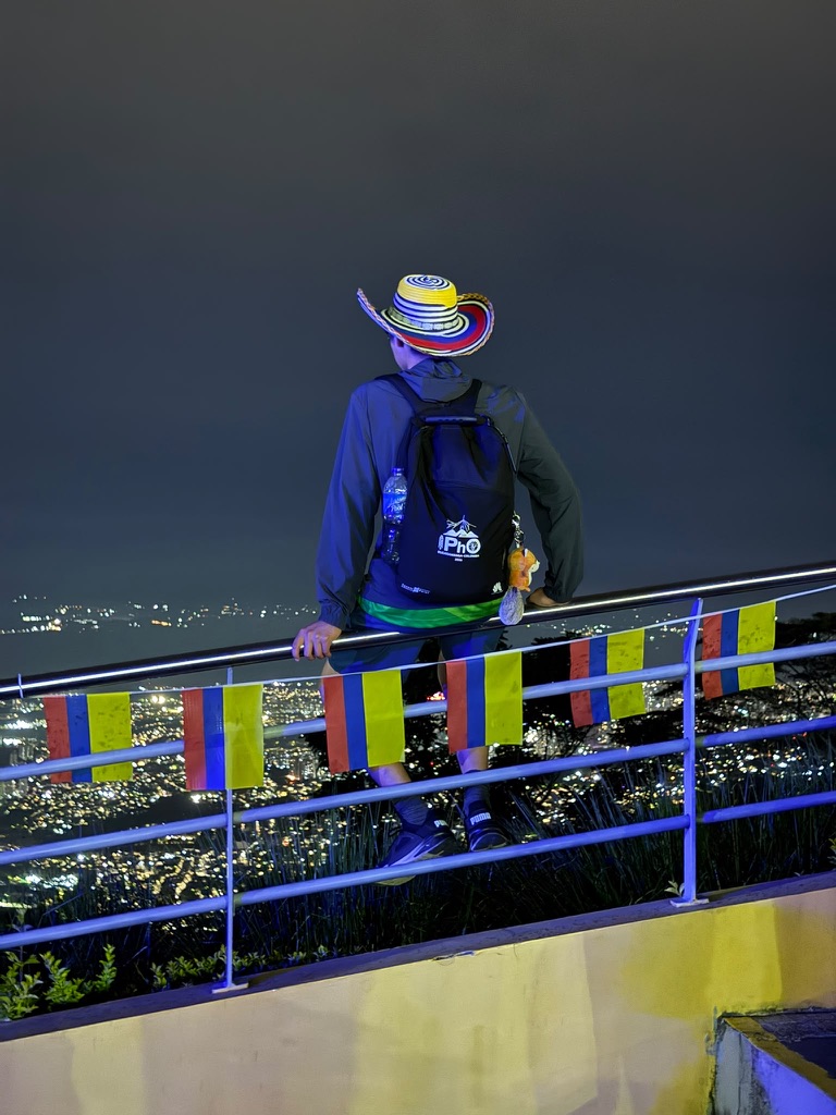 Ermuun at night, looking out over city lights, wearing an IPhO backpack